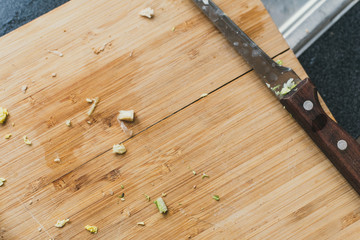 dirty wooden cutting board with a knife. Onions cut on a cutting board. remnants of greenery on a...