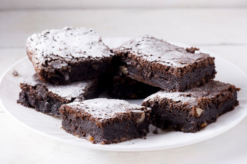 Delicious chocolate cake on a white plate, dusted with icing sugar. Homemade baking. Traditional American Pie.
