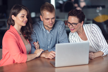Investment adviser giving a presentation to a friendly smiling young couple seated at her desk in the office