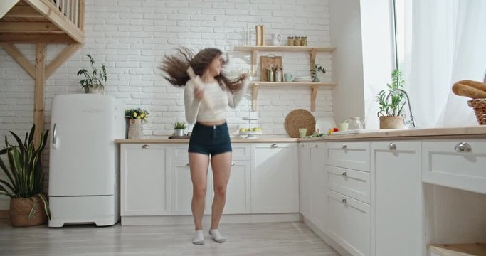 Pretty asian girl with curly hair crazily dancing to music while preparing lunch with positive smile on face - recreational pursuit slow motion 4k
