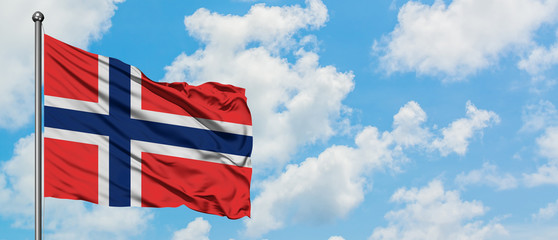 Bouvet Islands flag waving in the wind against white cloudy blue sky. Diplomacy concept, international relations.