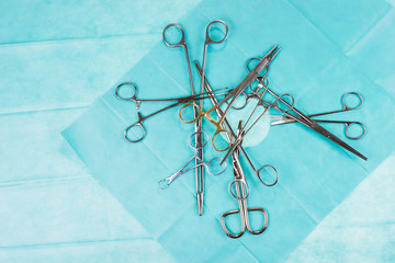 Chaos on the operating table. Surgical scissors and clamps on green gauze. Medical instruments