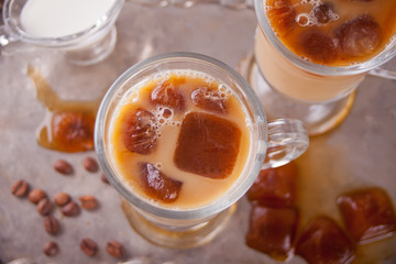 Iced latte coffee with ice cubes and coffee beans on a tray.