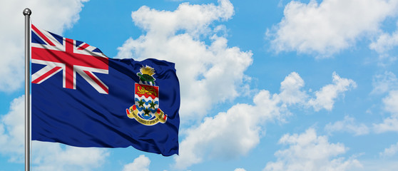 Cayman Islands flag waving in the wind against white cloudy blue sky. Diplomacy concept, international relations.