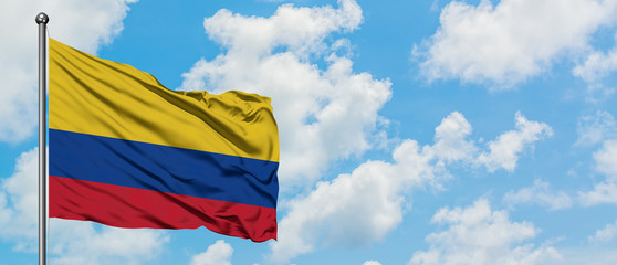 Colombia flag waving in the wind against white cloudy blue sky. Diplomacy concept, international relations.