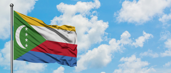 Comoros flag waving in the wind against white cloudy blue sky. Diplomacy concept, international relations.