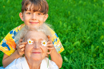 Happy boy with his beloved grandmother spend leisure time outdoors. The boy puts his grandmother to...