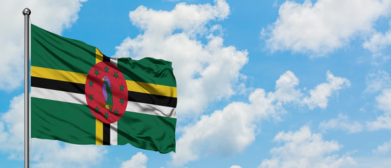 Dominica flag waving in the wind against white cloudy blue sky. Diplomacy concept, international...