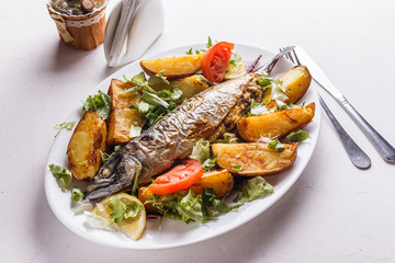 Baked stuffed fish with potatoes on the plate