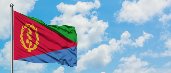 Eritrea flag waving in the wind against white cloudy blue sky. Diplomacy concept, international relations.