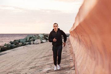 Young man jogging on a beach at sunrise. Motion blur effect. Concepts: well-being, vitality, healthy life, vacation, sport, training