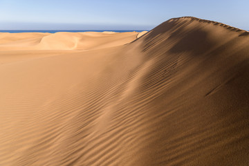 Fototapeta na wymiar Shades and sand drifts at the Maspalomas dunescape