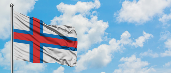 Faroe Islands flag waving in the wind against white cloudy blue sky. Diplomacy concept, international relations.
