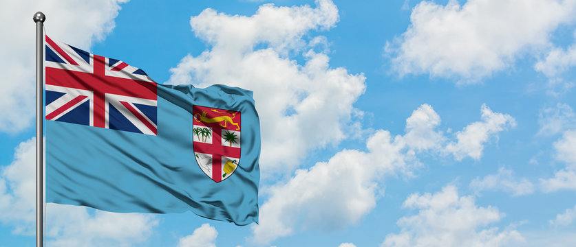 Fiji flag waving in the wind against white cloudy blue sky. Diplomacy concept, international relations. - Powered by Adobe