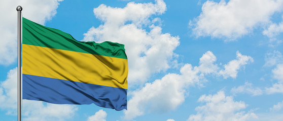 Gabon flag waving in the wind against white cloudy blue sky. Diplomacy concept, international relations.