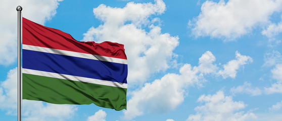 Fototapeta na wymiar Gambia flag waving in the wind against white cloudy blue sky. Diplomacy concept, international relations.