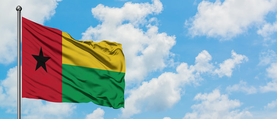 Guinea Bissau flag waving in the wind against white cloudy blue sky. Diplomacy concept, international relations.