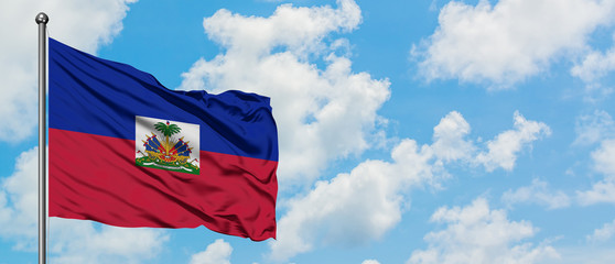 Haiti flag waving in the wind against white cloudy blue sky. Diplomacy concept, international relations.