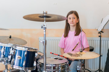 Little caucasian girl drummer playing the elettronic drum kit and shuoting. Teen girls are having...