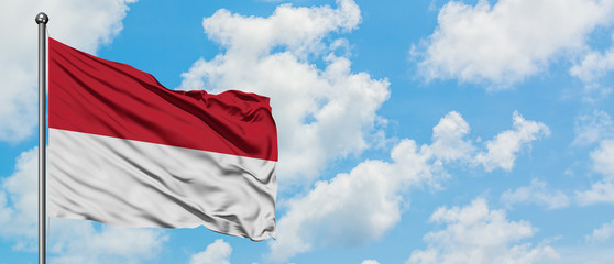 Indonesia flag waving in the wind against white cloudy blue sky. Diplomacy concept, international relations.