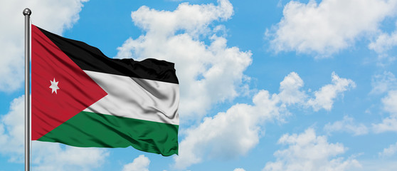 Jordan flag waving in the wind against white cloudy blue sky. Diplomacy concept, international relations.