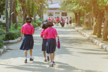 Back view of happiness primary girl students in pink shirt and blue skirt walk to classrooms with their friends.