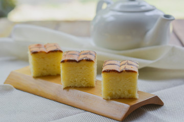 Cube cut of butter cake on wooden tray and table for served in party. Delicious dessert eat with tea and coffee in morning.