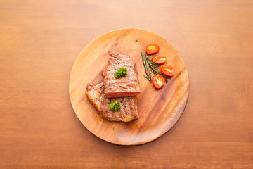 Fresh cooked half cut beef sirloin with cherry tomato and rosemary on top with parsley, Wood background