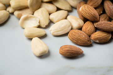 Mandeln als ungeschälte und blanchiert geschälte Nuss auf Marmor Hintergrund