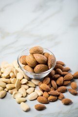 Mandeln als ganze Nuss, ungeschält und blanchiert geschält auf Marmor Hintergrund