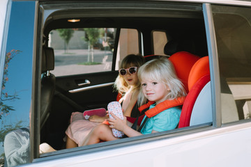 Two girls sitting in the car in car seats. Road safety.