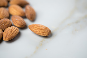Braune Mandeln in Glas Schale auf Marmor Hintergrund