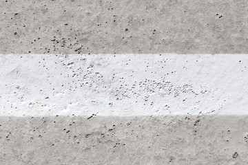 Grey concrete surface with wide white stripe in the middle.