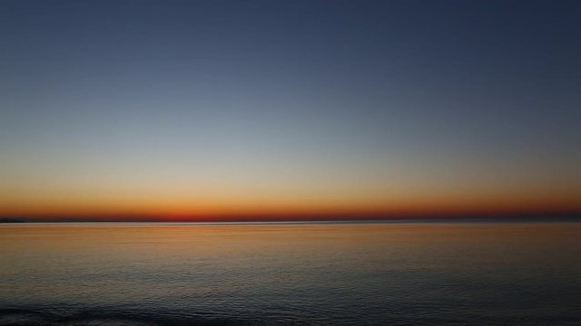 calm sea at the sunrise. small waves roll on the seashore with pebbles. beautiful dark blue morning sky over the sea and beach in Antalya, Turkey