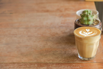 Latte art of coffee with cactus on wooden table , background