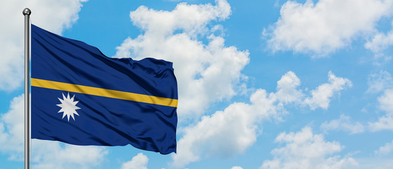 Nauru flag waving in the wind against white cloudy blue sky. Diplomacy concept, international relations.