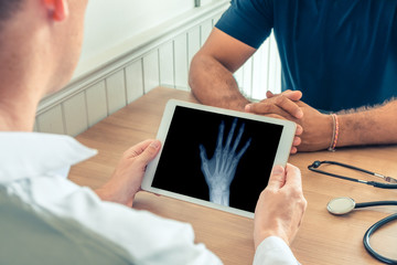 Doctor holding a digital tablet with x-ray of right hand of the patient