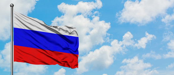 Russia flag waving in the wind against white cloudy blue sky. Diplomacy concept, international relations.
