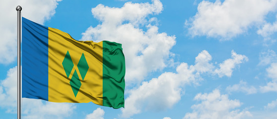 Saint Vincent And The Grenadines flag waving in the wind against white cloudy blue sky. Diplomacy...