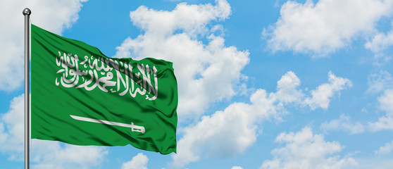 Saudi Arabia flag waving in the wind against white cloudy blue sky. Diplomacy concept, international relations.