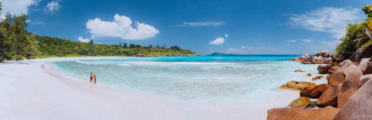 Panoramic shot of wide picturesque white sand beach, Seychelles, La Digue, Anse Cocos. Couple enyoing vocation time concept