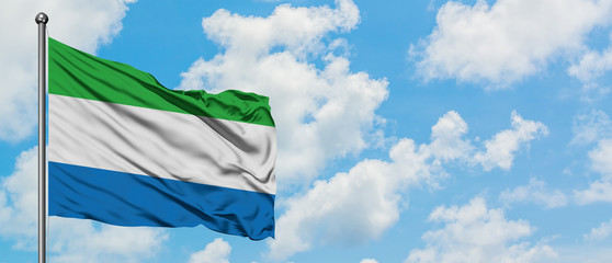 Sierra Leone flag waving in the wind against white cloudy blue sky. Diplomacy concept, international relations.