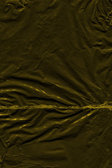 Transparent yellow plastic wrap on the black background. Plastic shopping bag texture. Reusable trash and waste.