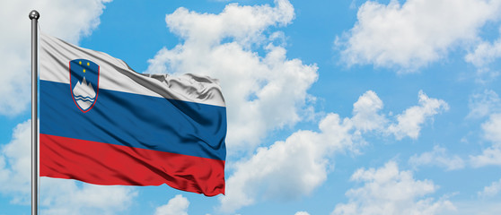 Slovenia flag waving in the wind against white cloudy blue sky. Diplomacy concept, international relations.