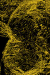 Transparent yellow plastic wrap on the black background. Plastic shopping bag texture. Reusable trash and waste.