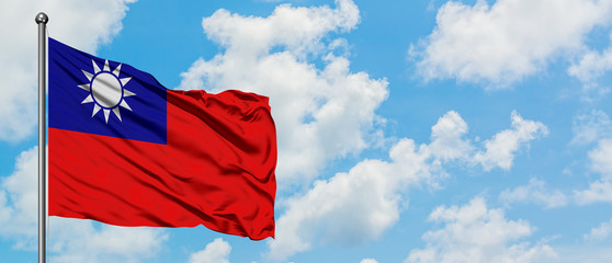 Taiwan flag waving in the wind against white cloudy blue sky. Diplomacy concept, international relations.