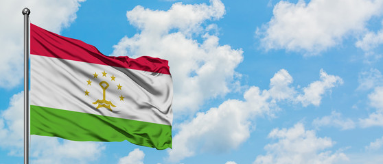 Tajikistan flag waving in the wind against white cloudy blue sky. Diplomacy concept, international relations.