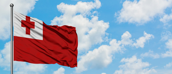 Tonga flag waving in the wind against white cloudy blue sky. Diplomacy concept, international relations.