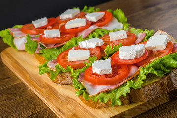 Delicious sandwich and lager beer on wooden table with dark background.