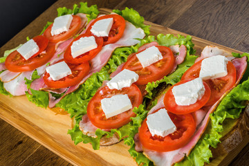 Delicious sandwich and lager beer on wooden table with dark background.